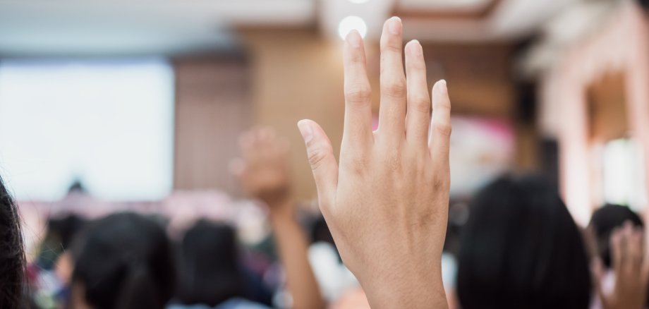 Audience or students raising hands up at conference to answer qu